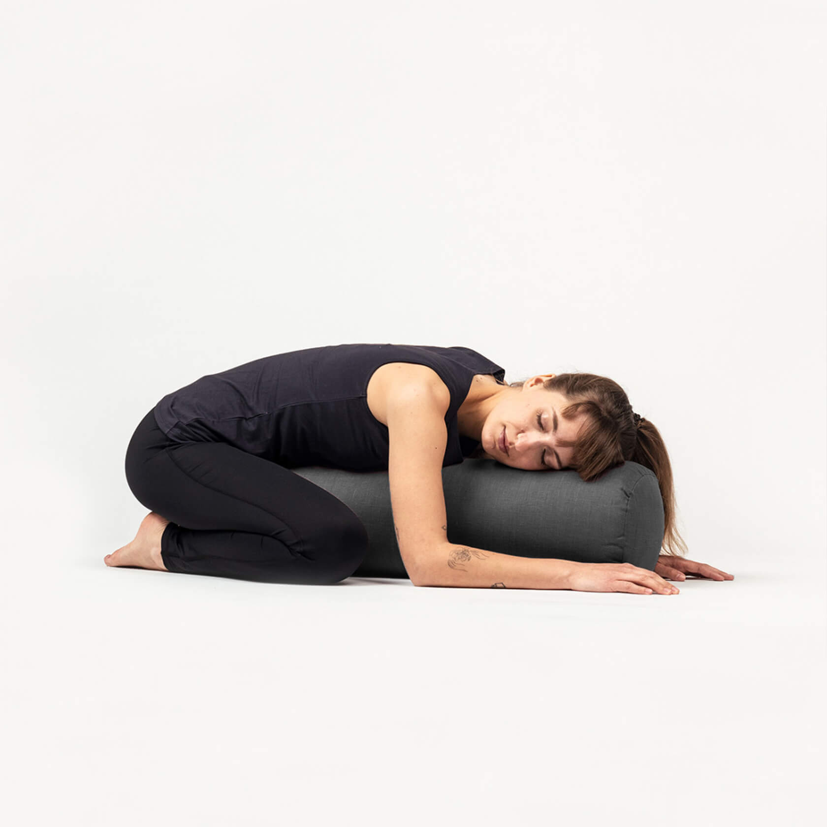 Woman resting in child&#39;s pose on round yoga bolster