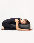 Woman resting in child's pose on round yoga bolster